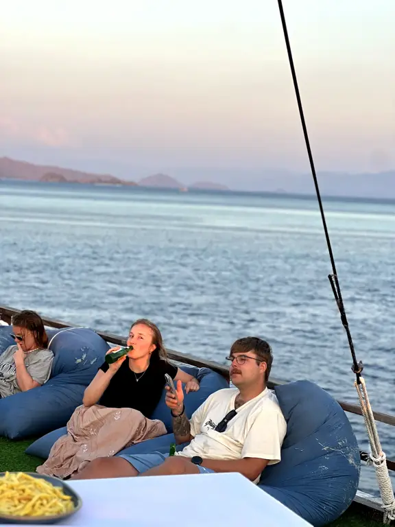 Tamu bersantai di bean bag dek kapal saat senja