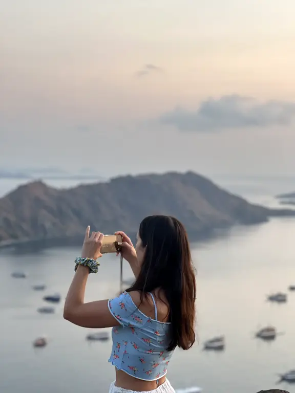 Tamu memotret teluk berisi kapal saat senja