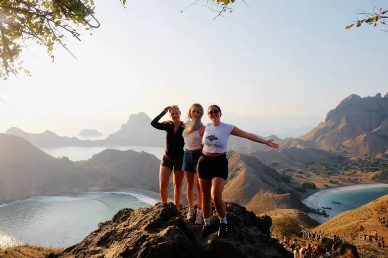 Tiga tamu berfoto di puncak Padar dengan tiga teluk di belakangnya