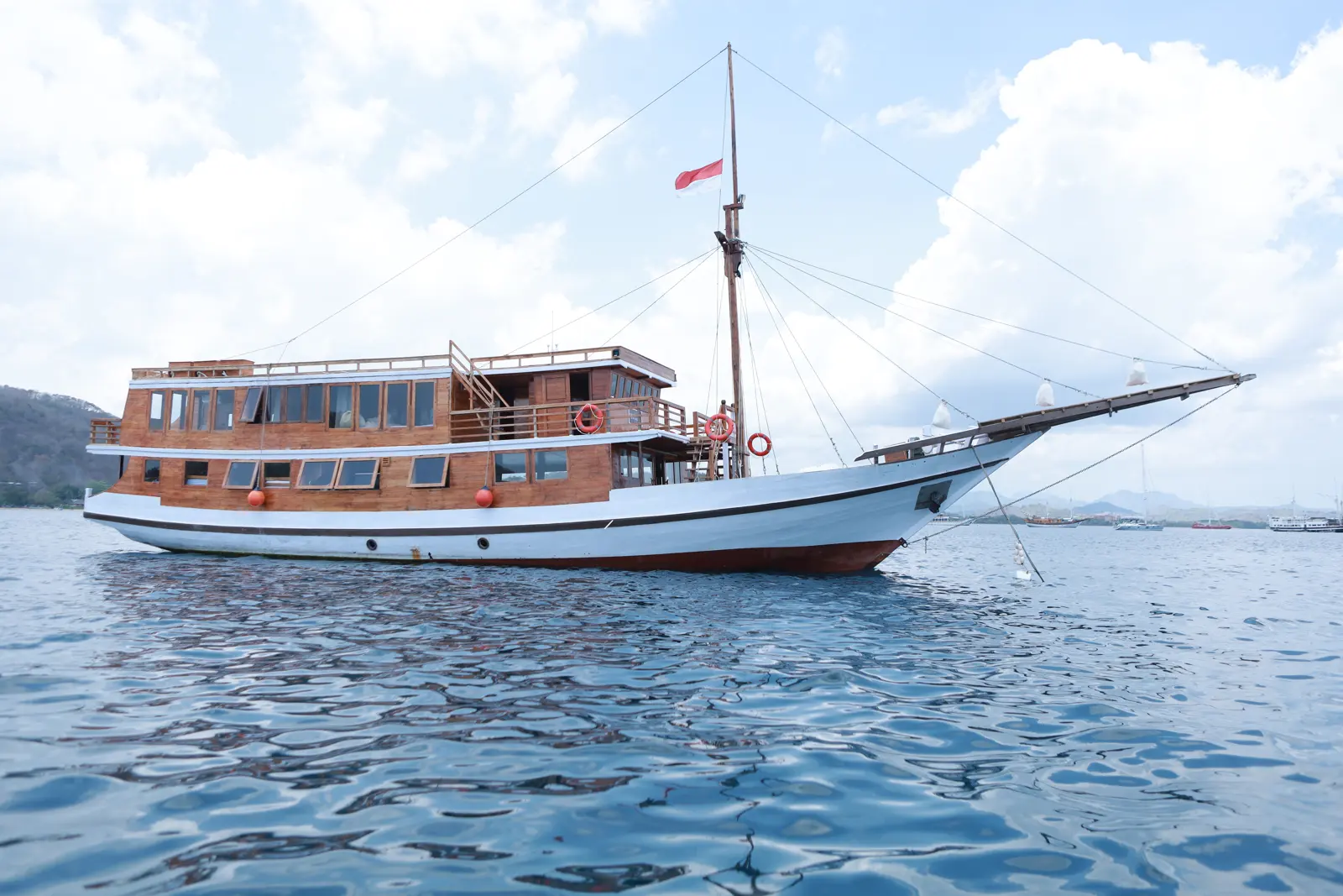 Aimar white hull and two wooden decks seen from the side on calm water
