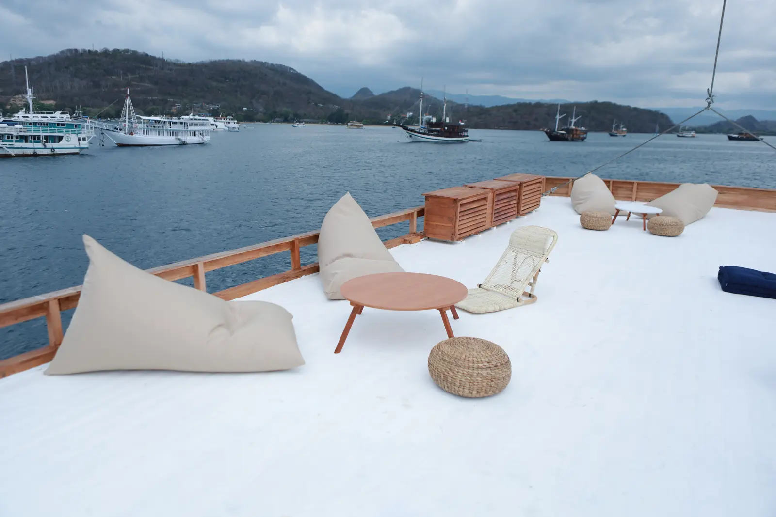 Aimar white sundeck with beanbags and low tables facing Labuan Bajo bay