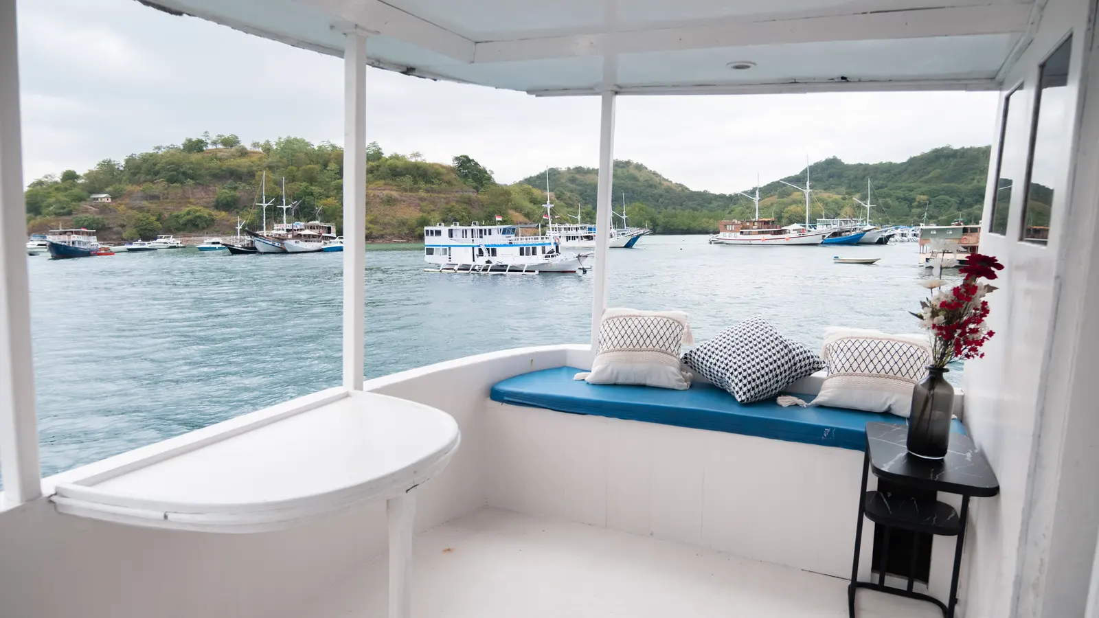 Balkon pribadi Master Cabin Poseidon dengan bangku berbantal menghadap teluk