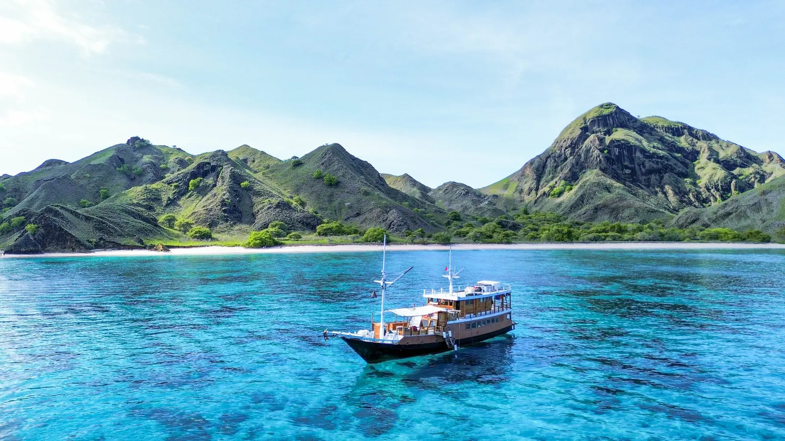 Capt Octopus di teluk Padar dengan perbukitan hijau di belakangnya