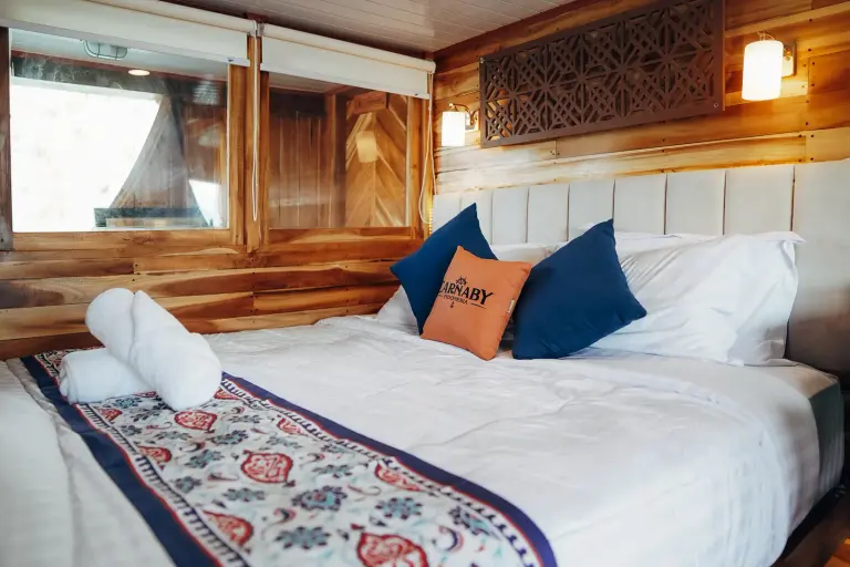 Carnaby II upper-deck Deluxe Cabin Bulukumba, a double bed beside a sea window