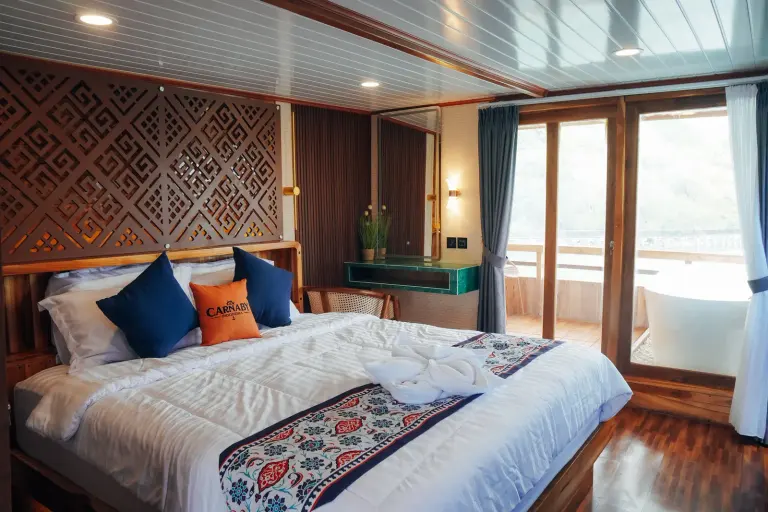 Carnaby II upper-deck Master Cabin, a double bed with a carved headboard and glass doors to the balcony