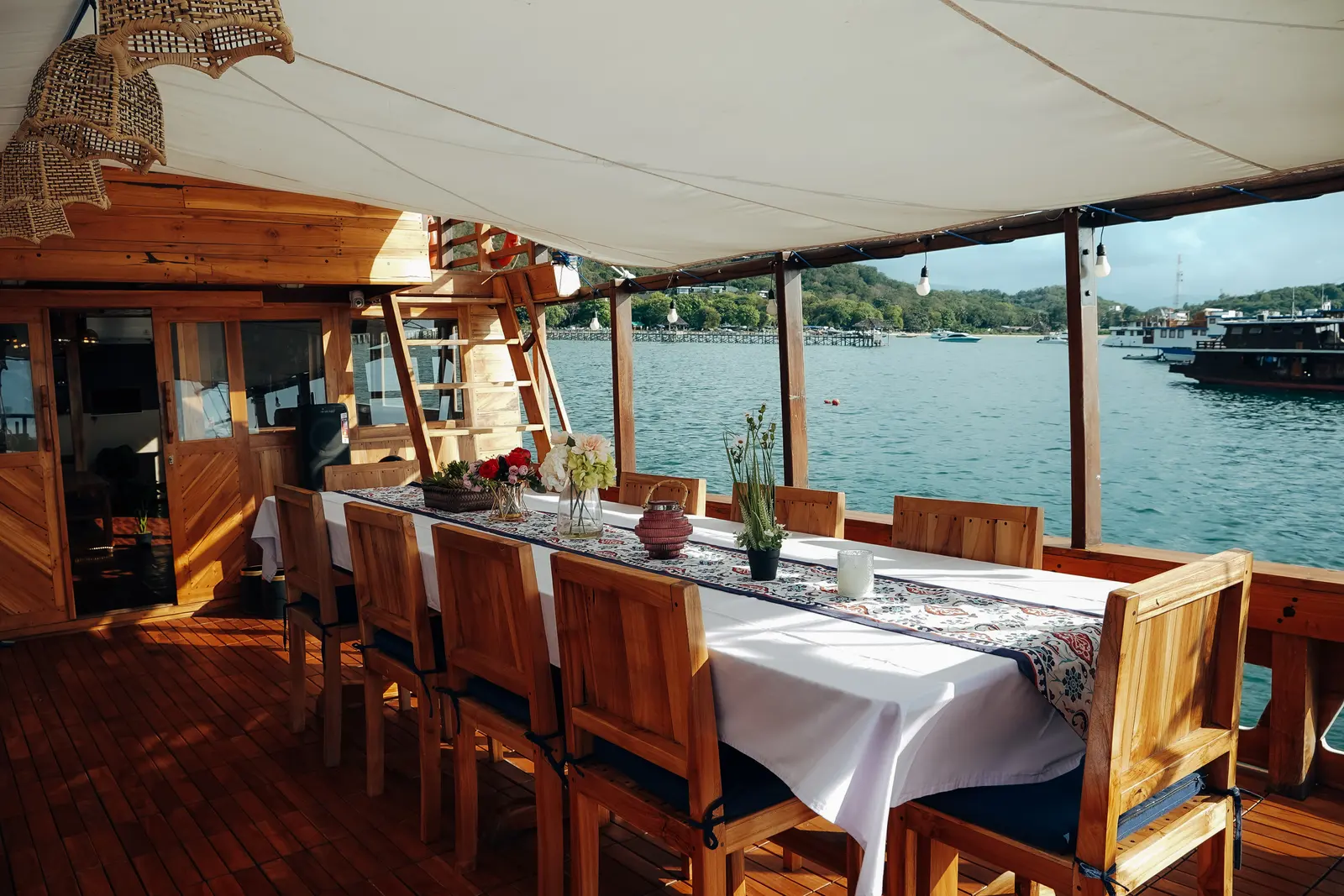 Carnaby II open-air dining area, a long dressed table and wooden chairs facing the sea