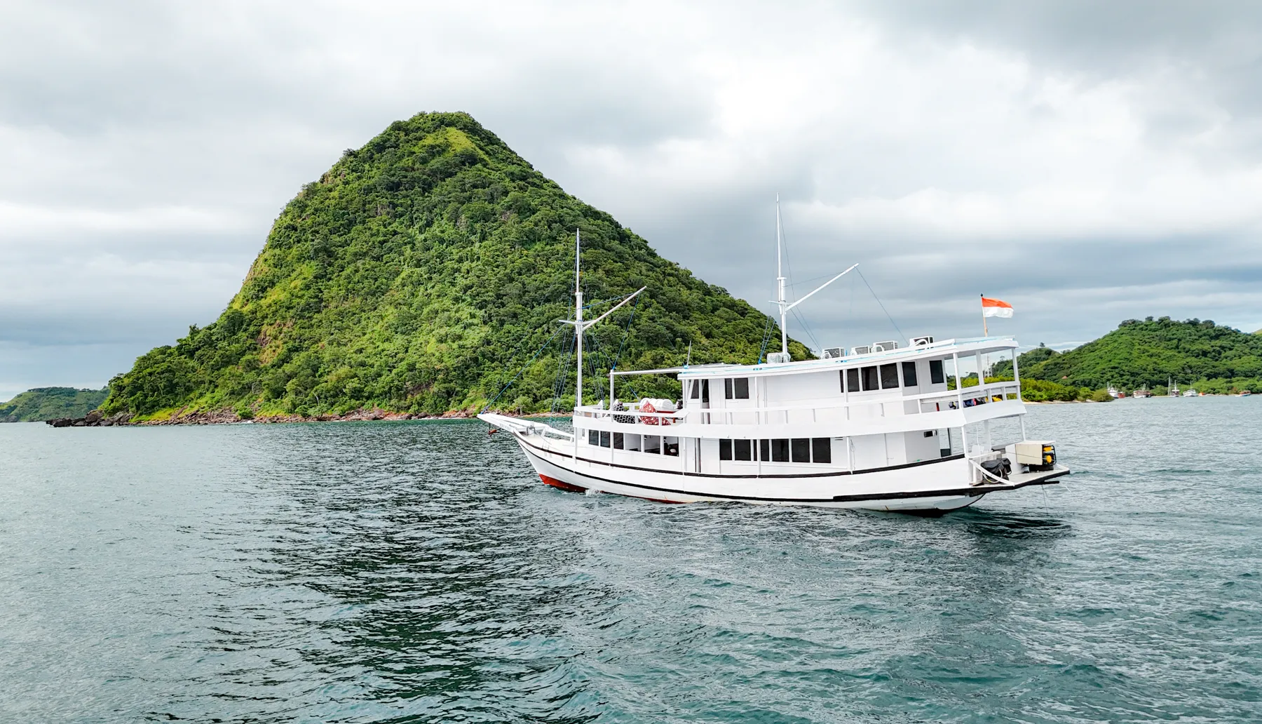 白色木船 Deden Putra 停泊在纳闽巴霍海域,背后是青翠山丘