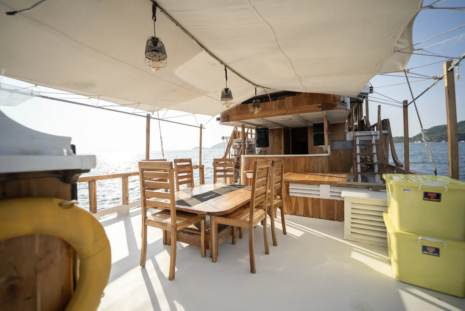 Wooden dining table on the NK Jaya outer deck, shaded under a white awning