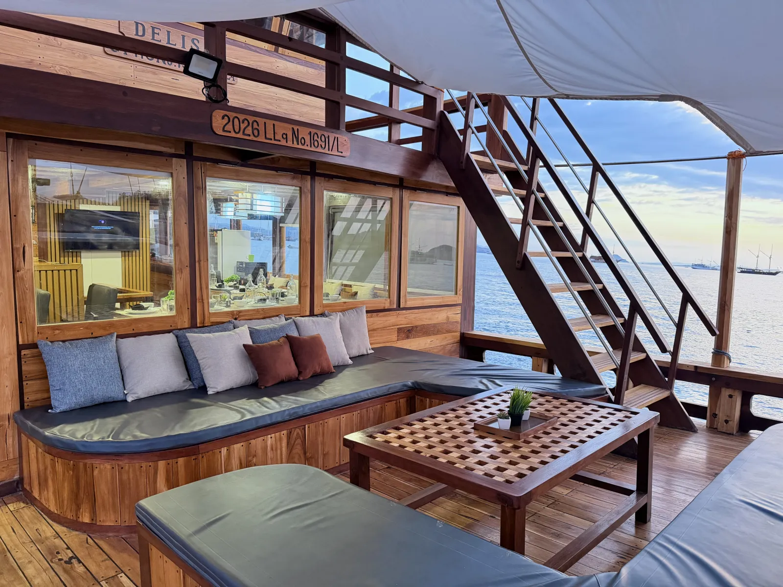 Delisa deck lounge, cushioned sofa around a wooden table under the canopy
