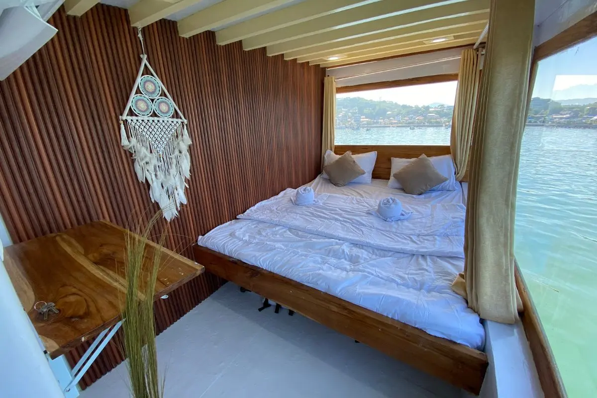 Kabin Deluxe Gajah Putih, kasur double dan hiasan dreamcatcher di dinding kayu