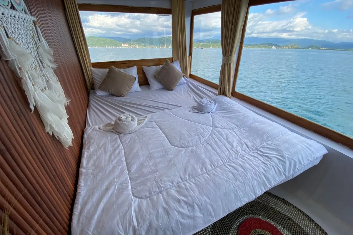 Kabin Deluxe Gajah Putih dengan kasur double menghadap jendela laut