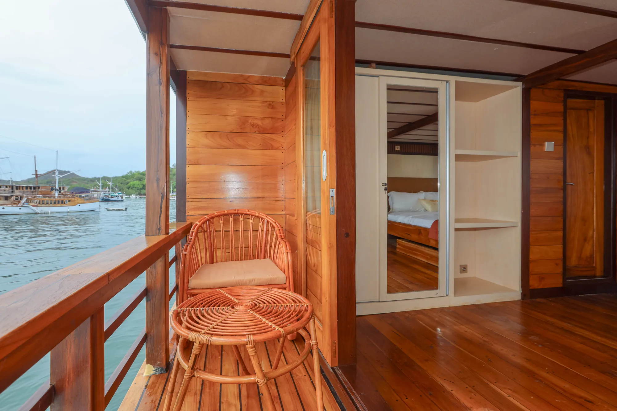 The Elrora Deluxe Cabin balcony with a rattan chair facing the harbour