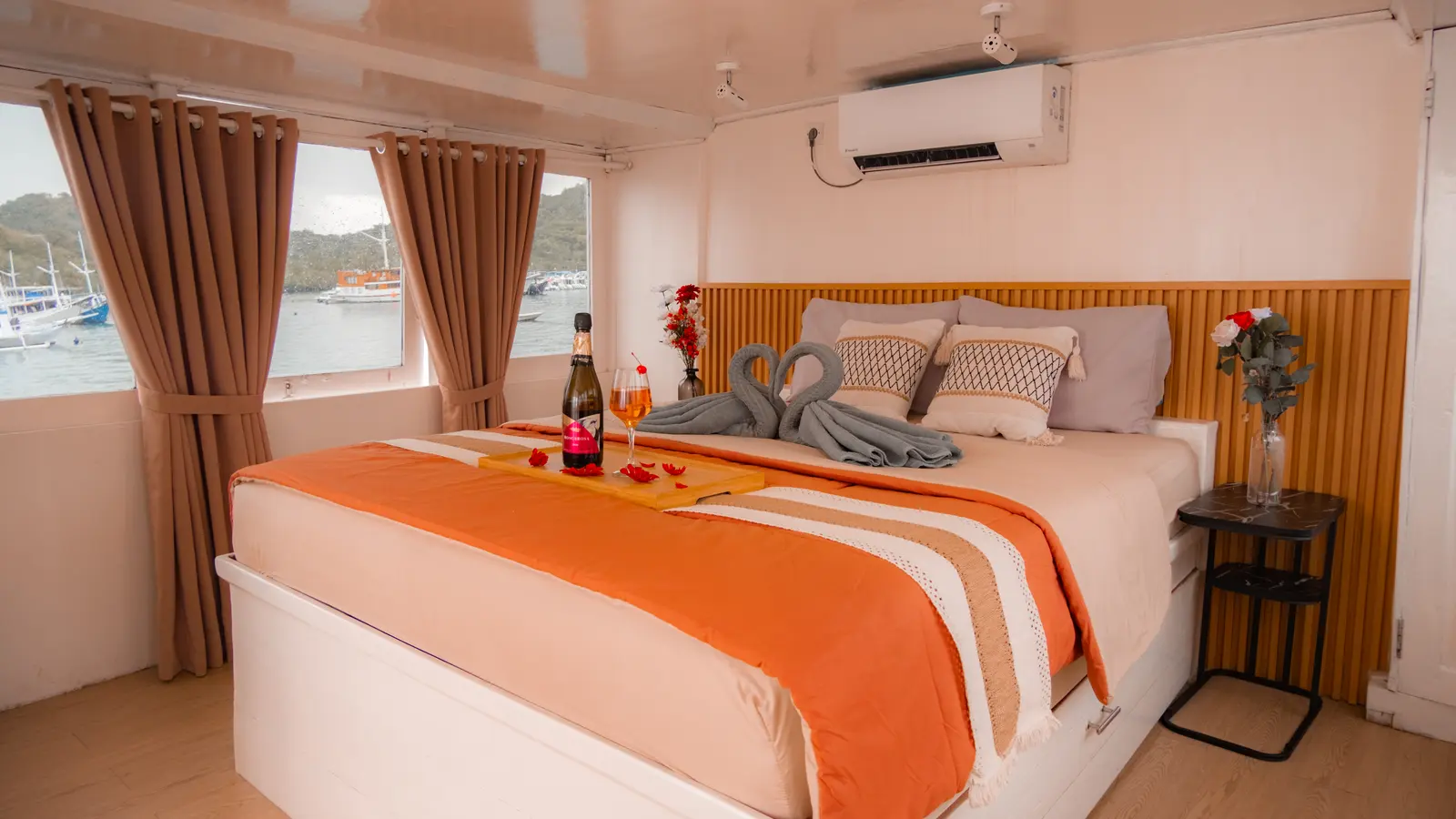 Master Cabin Poseidon Giona, ranjang double bersprei oranye dan jendela ke pelabuhan