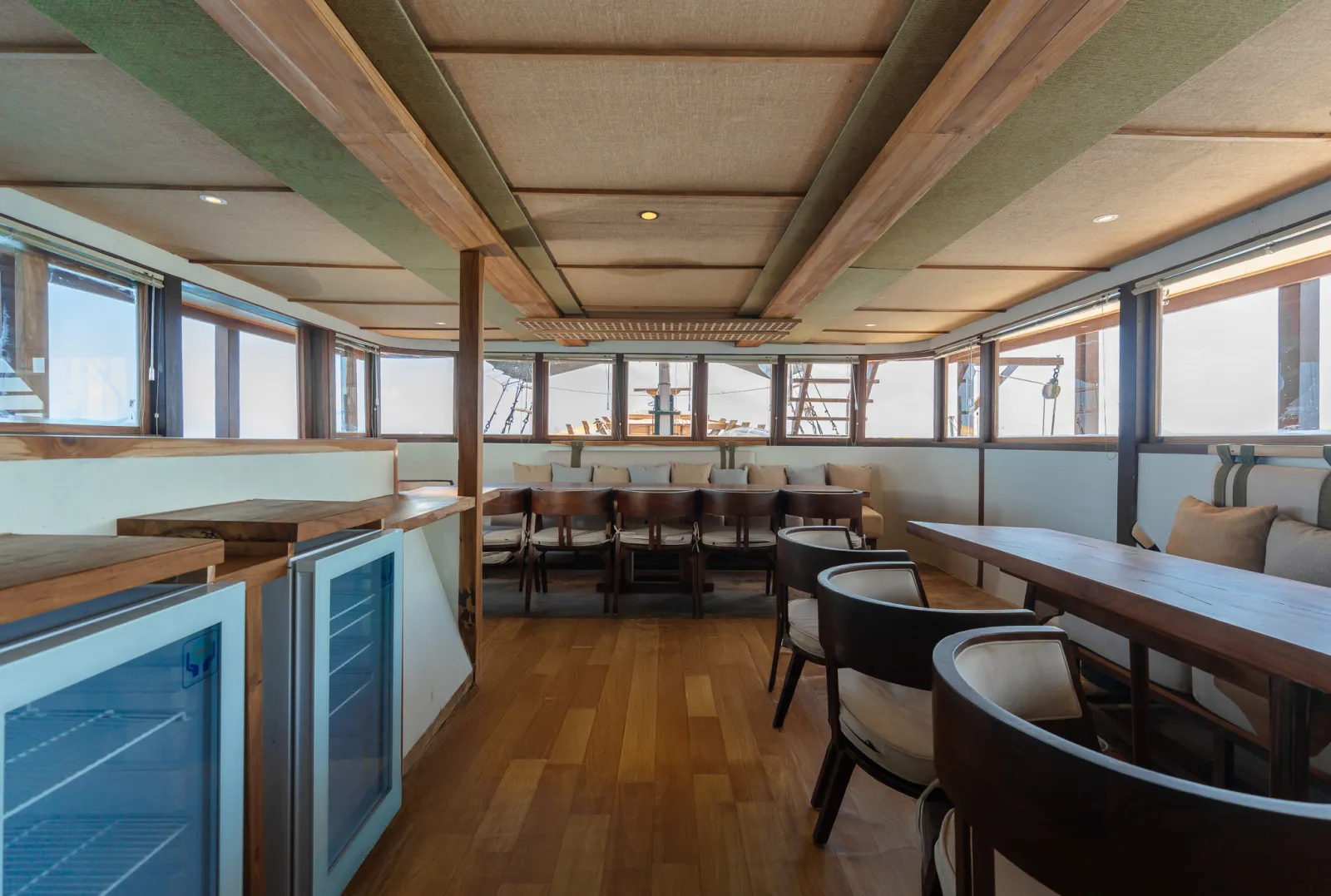 Indoor dining room on Marea, a long wooden table and wide sea windows