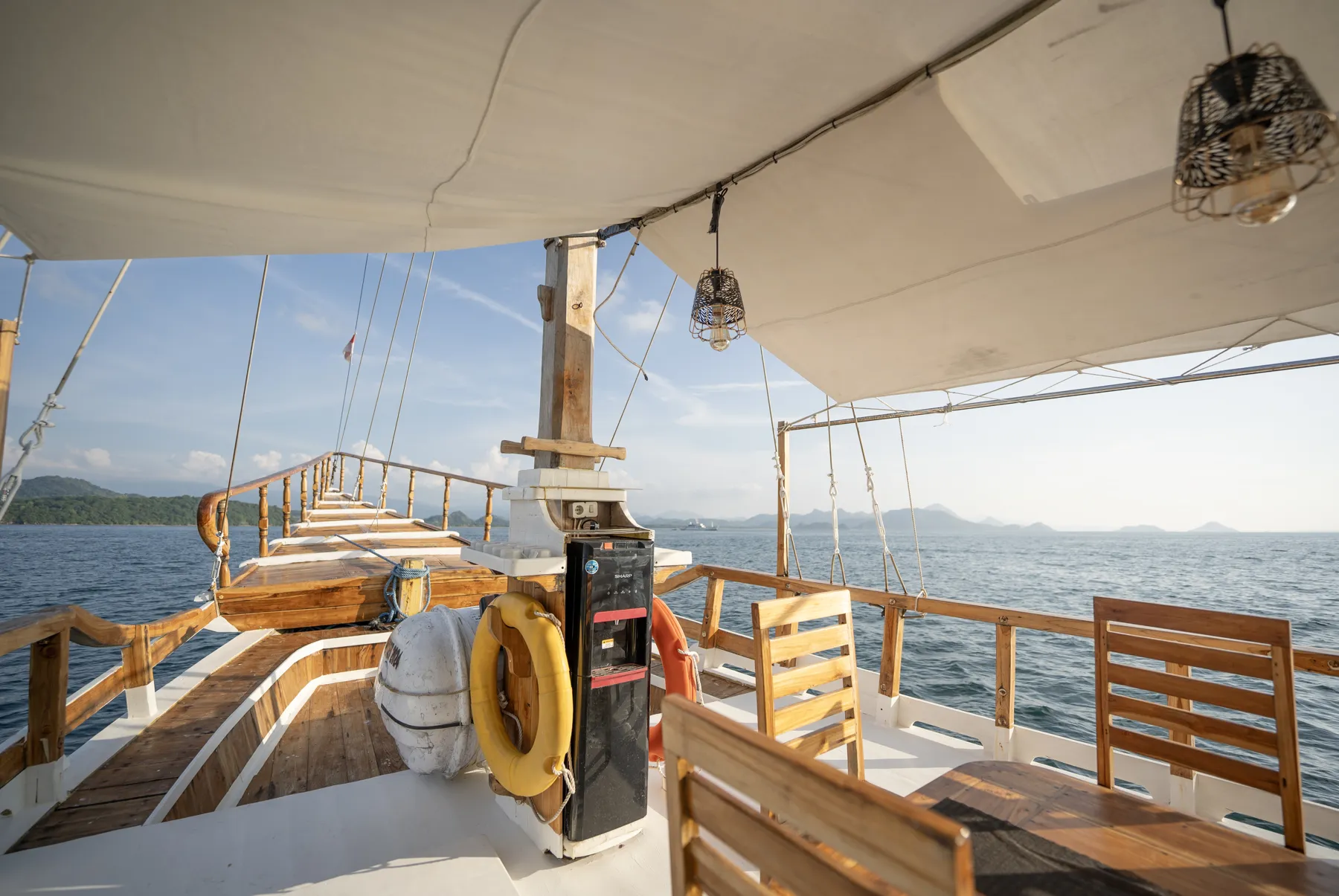 The NK Jaya outer deck with a wooden dining table under the canopy