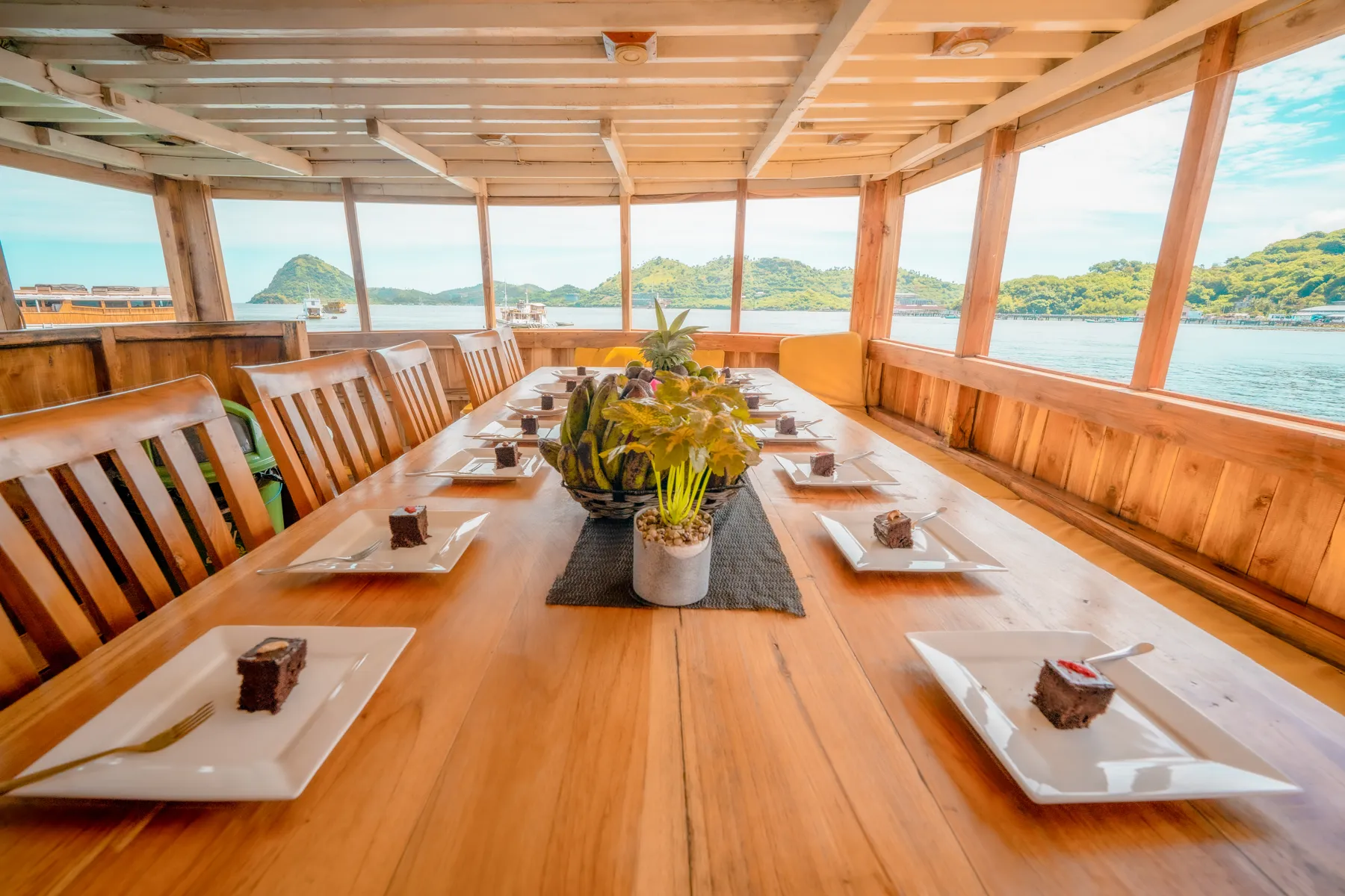 The NK Jaya indoor dining room with a long wooden table and windows all round
