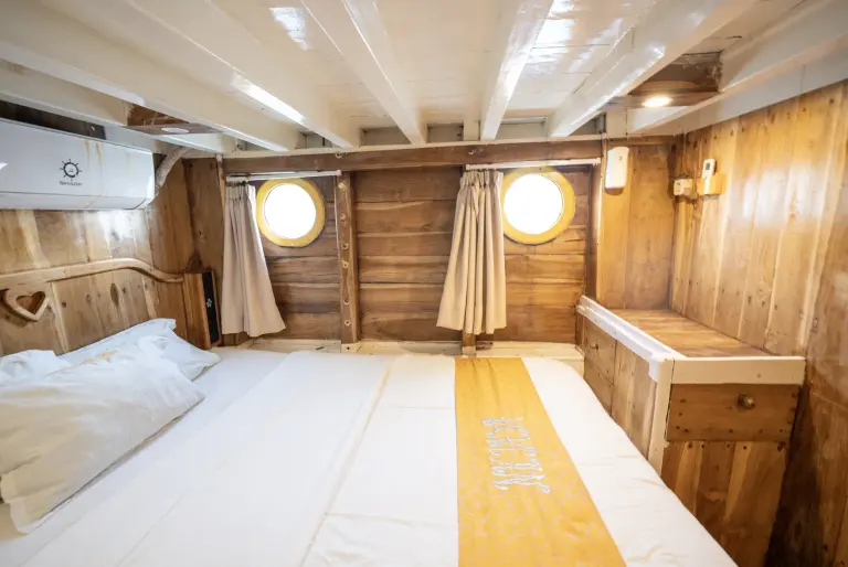 An NK Jaya Superior cabin on the lower deck, a queen bed and wooden walls