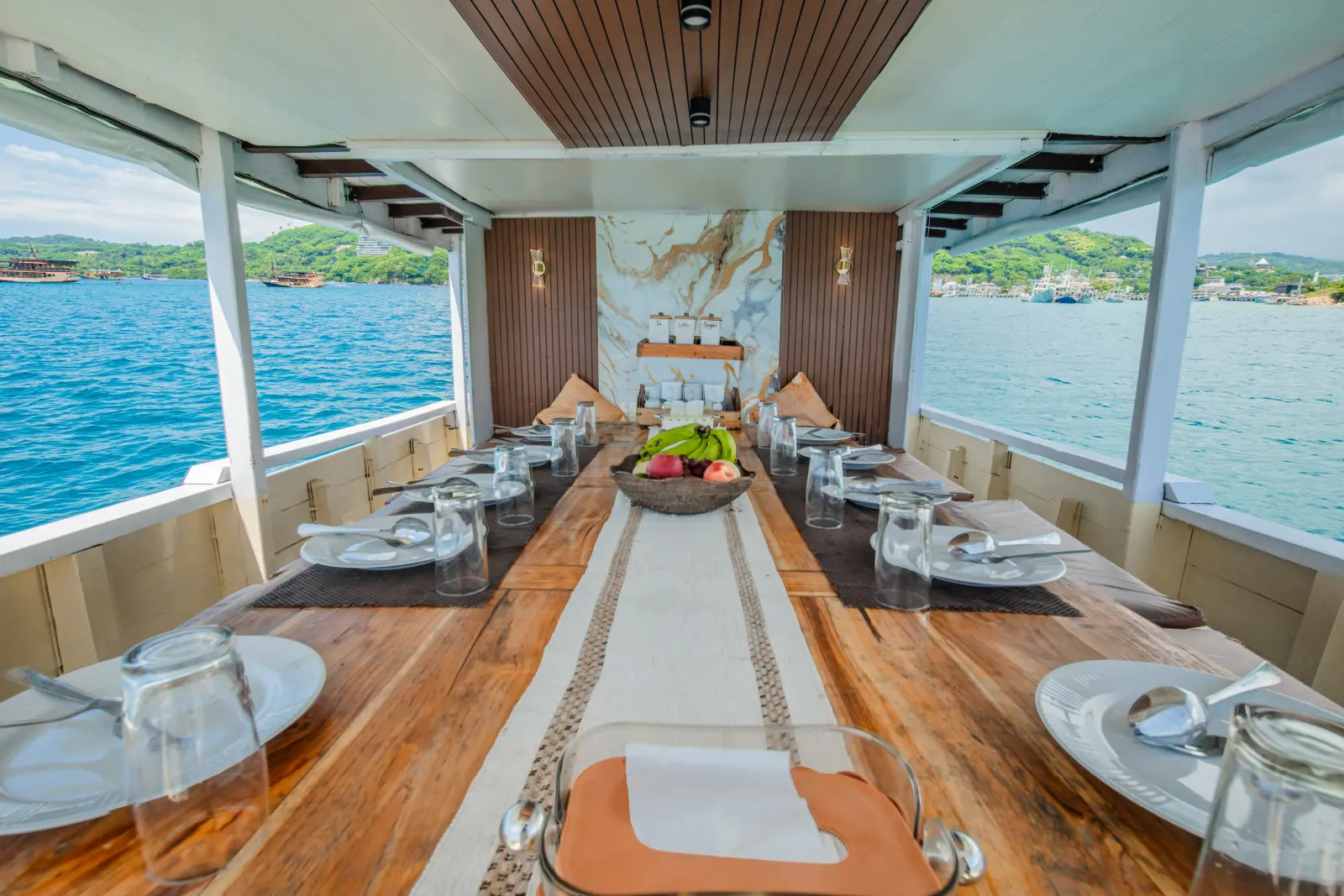 The Nusantara Karya dining room, a long wooden table set with plates and sea views