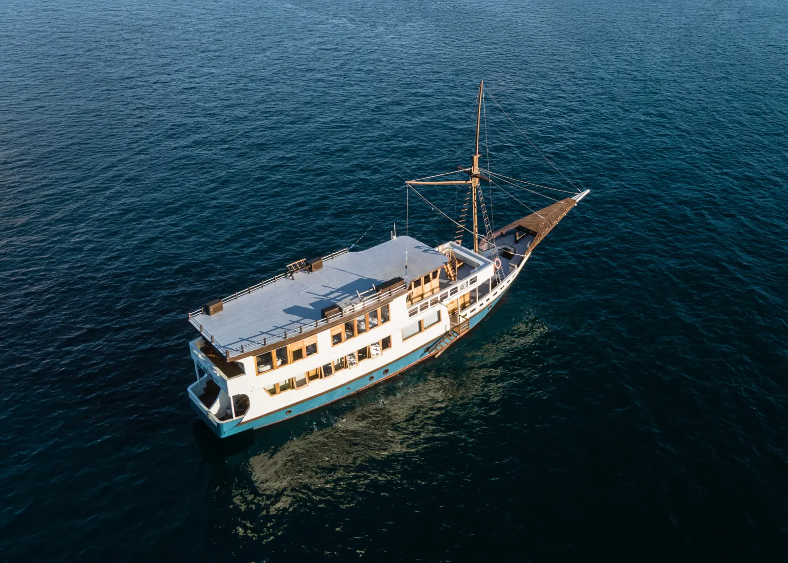 Raja Bintang 03 at anchor on calm water, showing the white-roofed top deck and long bow