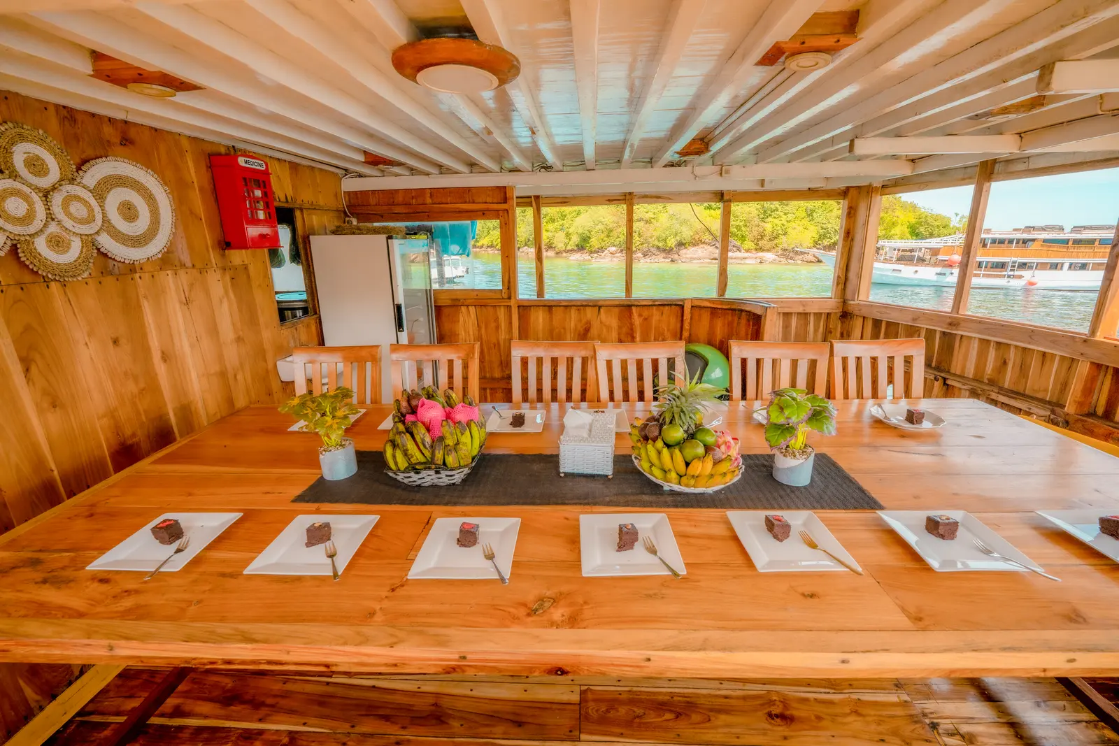 NK Jaya dining room with a long wooden table, fruit baskets and plates of cake set for guests