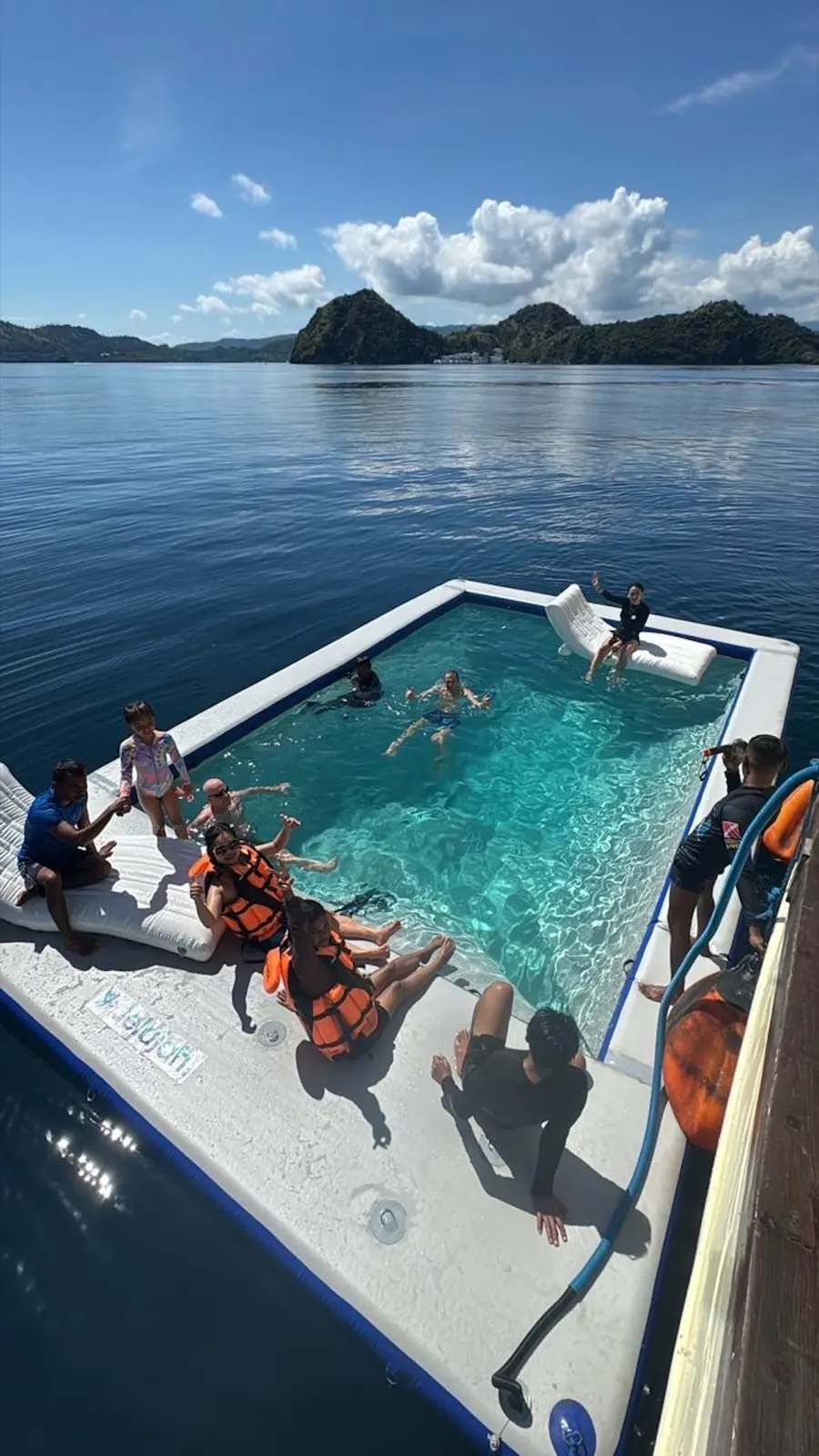 Guests swimming in the Leticia deck pool against hilly islands