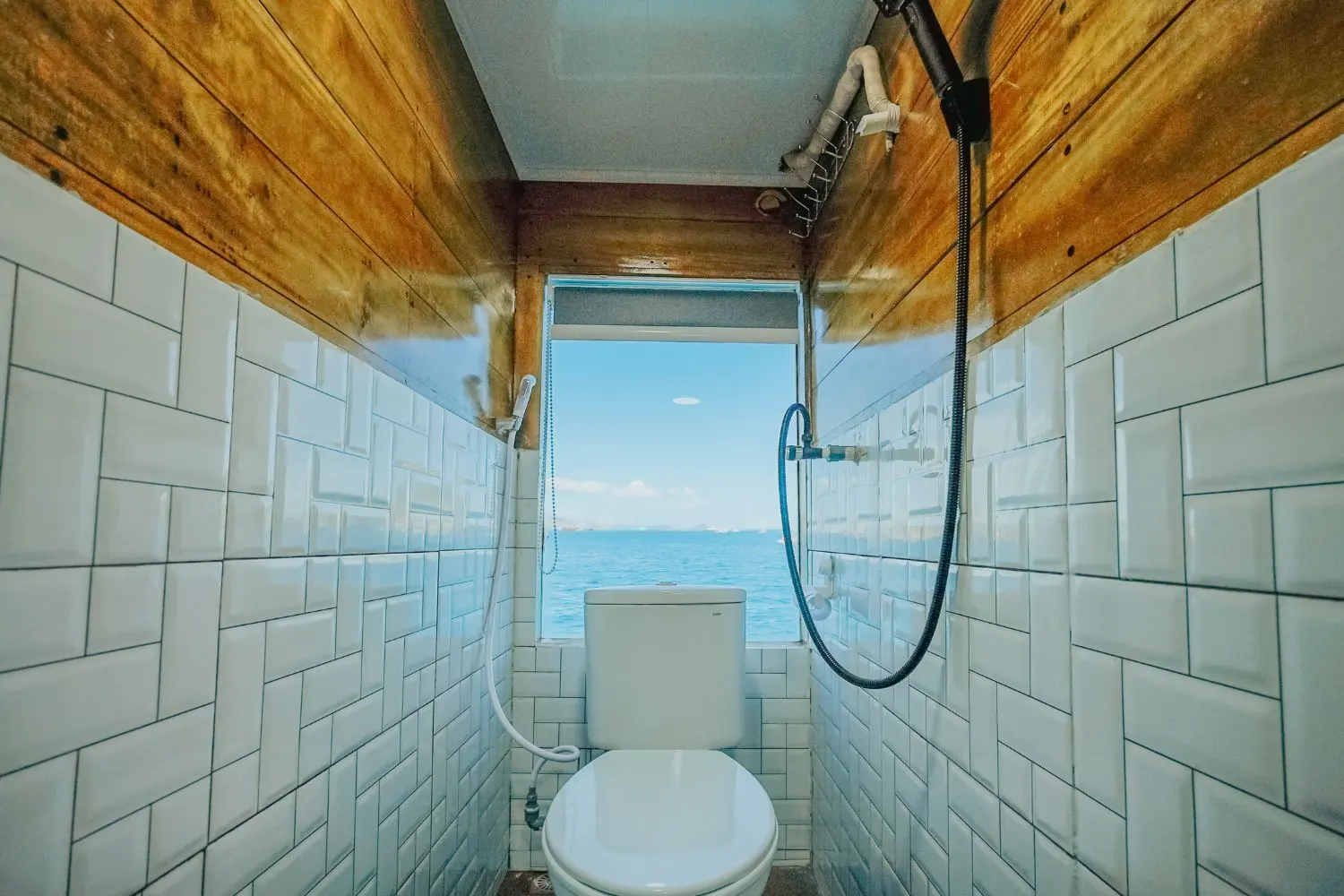 Kamar mandi dalam Segara berkeramik putih dengan shower dan kloset duduk
