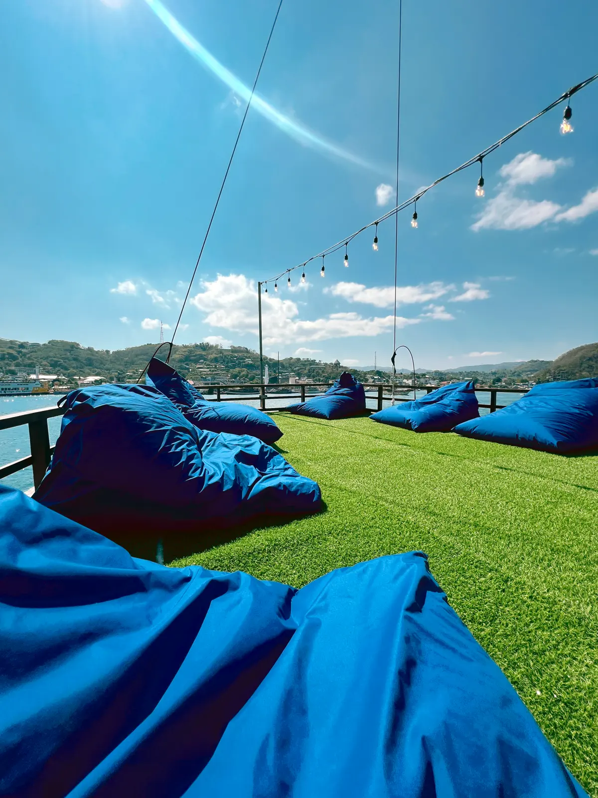 Sundeck Leticia dengan bean bag biru di atas rumput sintetis