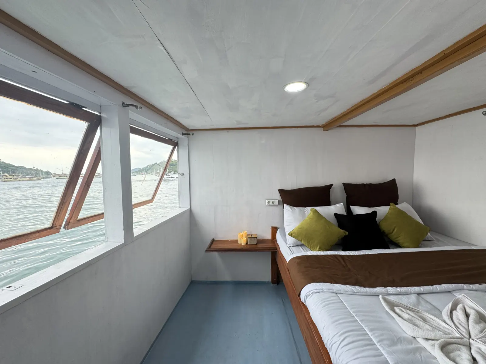 Umami Deluxe Cabin, a double bed beside a wide sea-facing window
