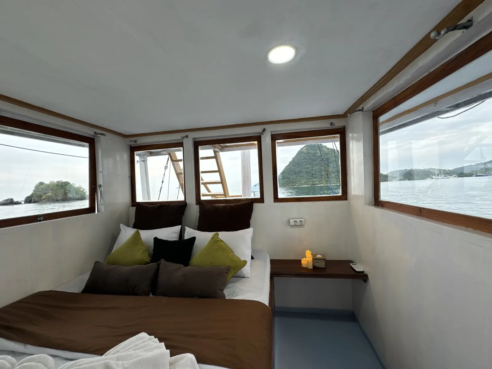 Umami Suite Cabin, a double bed with green cushions and sea windows on three sides